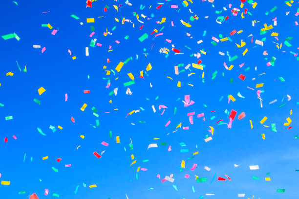 istock multicolored confetti on clear blue sky background. Concept of h 1337108037