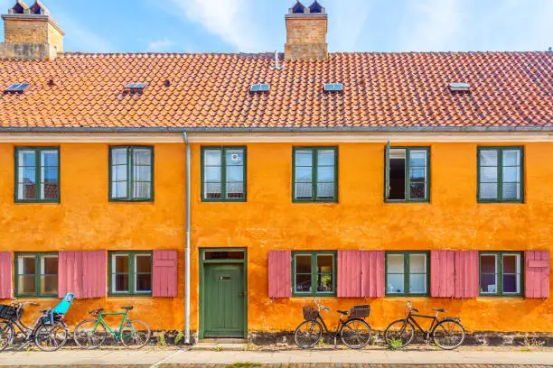Photo of Old yellow house of Nyboder district with bikes. Old Medieval district in Copenhagen, Denmark. Picturesque of Copenhagen.