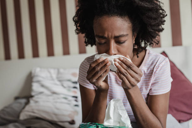 istock Woman with flu in bed blowing nose 1337111751