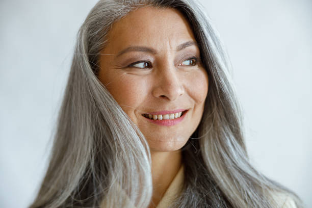 istock Asian lady with loose grey hair poses for camera on light background 1337111767