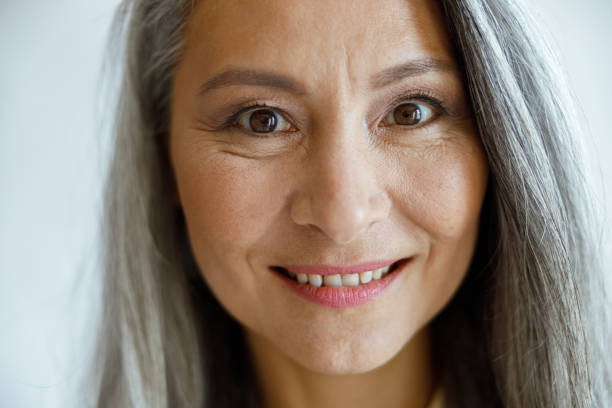 istock Cheerful silver haired lady with makeup looks into camera on light grey background 1337111772