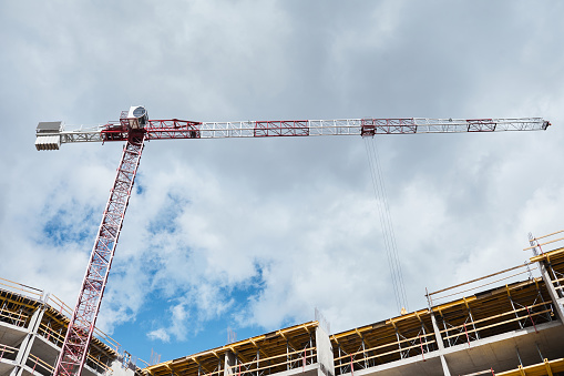 Low angle shot of residential building under construction with construction crane against blue sky, copy space