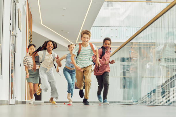 Kids Running in School Full length portrait of multi-ethnic group of schoolkids running towards camera indoors and smiling happily, copy space school children photos stock pictures, royalty-free photos & images