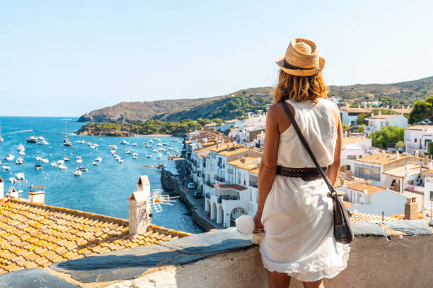 A young woman on vacation looking at the city of Cadaques from a viewpoint, Costa Brava of Catalonia, Gerona, Mediterranean Sea. Spain stock photo