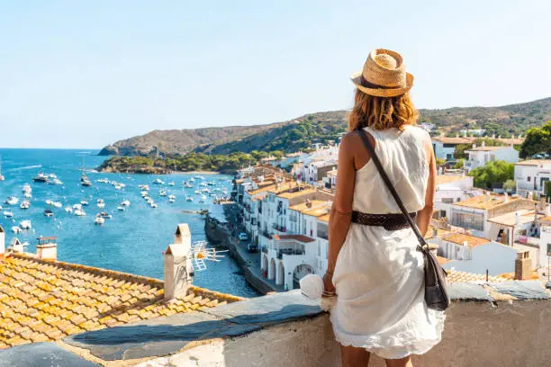 A young woman on vacation looking at the city of Cadaques from a viewpoint, Costa Brava of Catalonia, Gerona, Mediterranean Sea. Spain