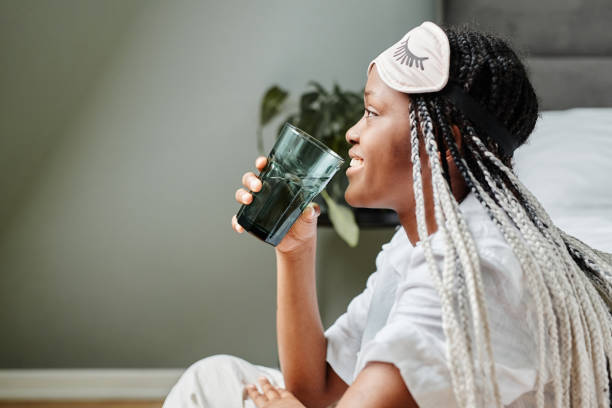 Hydration in Morning Side view portrait of young African-American woman drinking water in morning and smiling happily, copy space wake water stock pictures, royalty-free photos & images