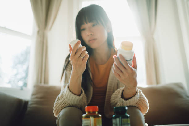 mujer asiática eligiendo entre suplementos - drug label fotografías e imágenes de stock