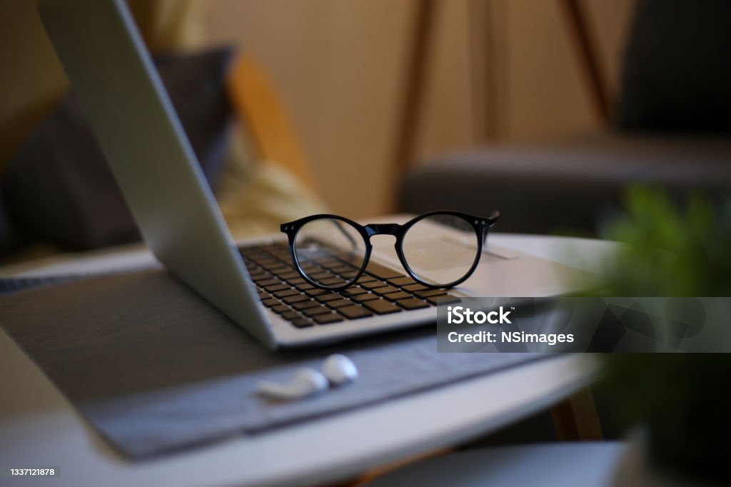 Side view of office desk with glasses, laptop and other items stock photo Close up of wooden desktop with glasses, laptop,and other items on office space background, selective focus Creative Director Stock Photo