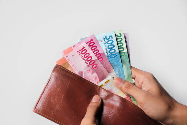 mano che mostra i soldi della rupia dal portafoglio isolato su sfondo bianco - indonesian currency foto e immagini stock
