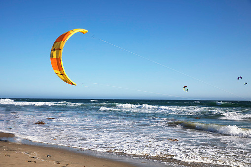 Female kiteboarder holds on to the handle of the kite and overcomes wave after wave on her surfboard