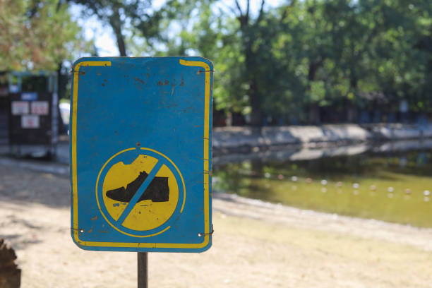 A sign prohibiting walking in shoes on a sandy beach. Blurred nature background.