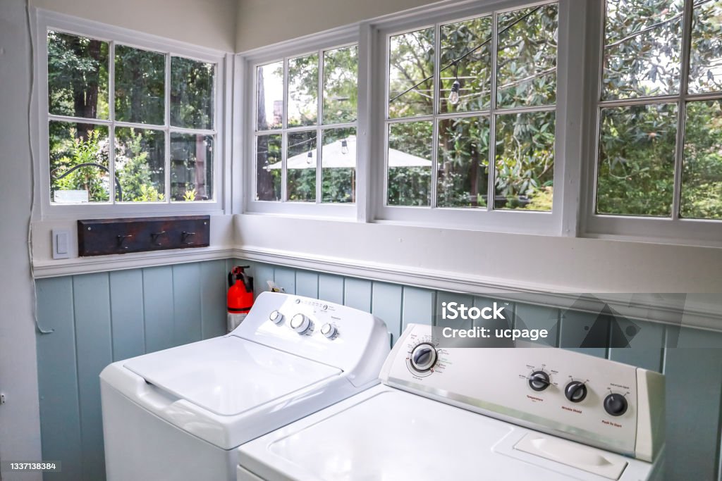 A vintage laundry room filled with windows and natural light A vintage laundry room filled with windows and natural light and a washer and dryer. Utility Room Stock Photo