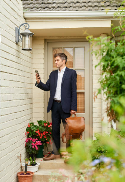 риэлтор проверяет свой телефон у входной двери дома на продажу - telephone locking lock unlocking стоковые фото и изображения