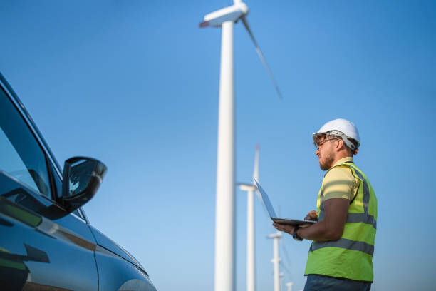istock Technician standing in a field at a wind farm using laptop 1337144225