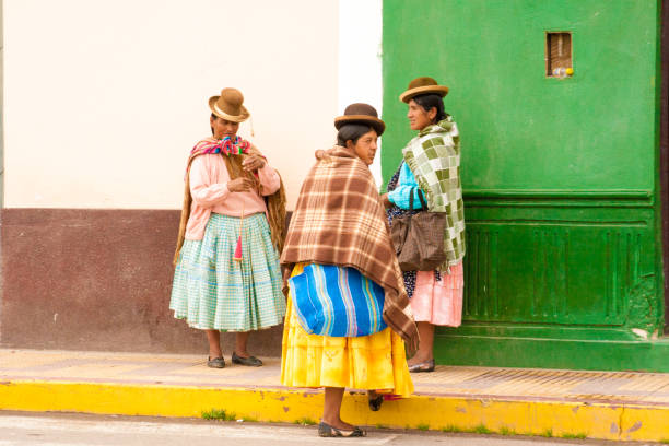 Puno, Peru: Three Quechua women chatting near a colorful wall in the Puno region of Peru.