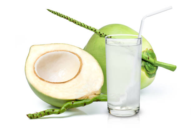 coconut water and  green coconut fruit isolated on white background. Glass of coconut juice with straw and young green coconut fruit isolated on white background. fruit of coconut tree stock pictures, royalty-free photos & images