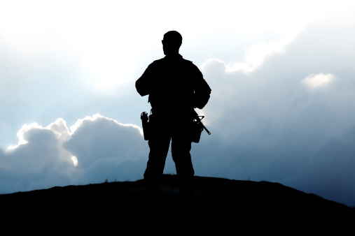A lone soldier stands gaurd on a hilltop.