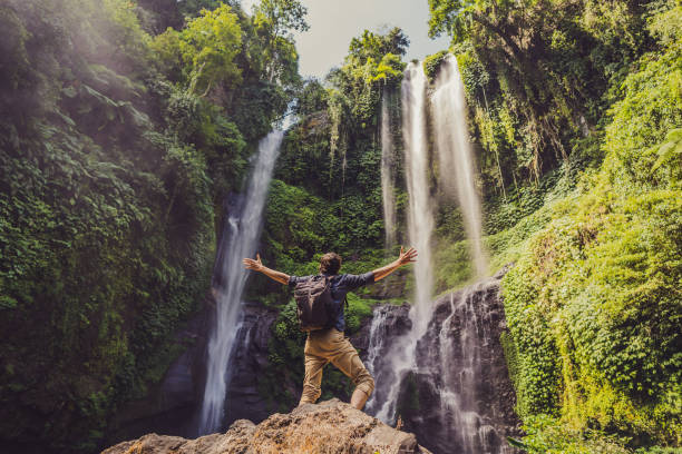 Photo of Man in turquoise dress at the Sekumpul waterfalls in jungles on Bali island, Indonesia. Bali Travel Concept