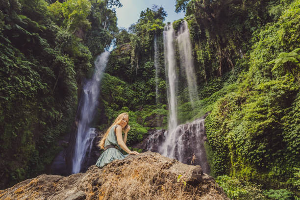woman in turquoise dress at the sekumpul waterfalls in jungles on bali island, indonesia. bali travel concept - stream forest river waterfall imagens e fotografias de stock