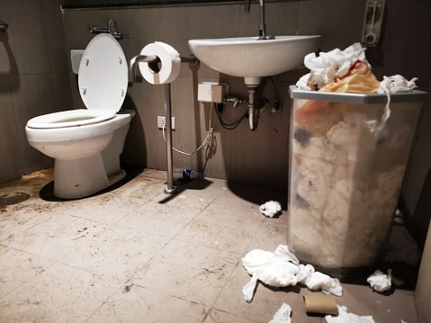 The public toilet room is littered with dirty things
