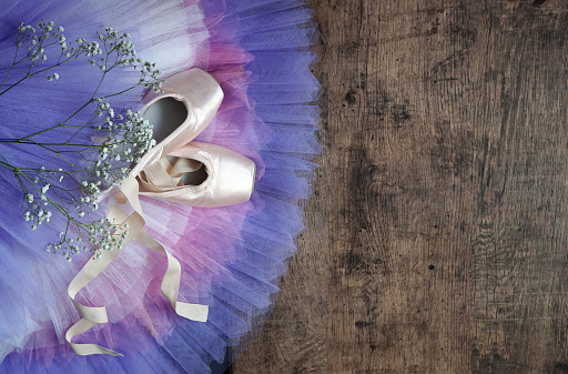 point shoes with color shirts on wooden floor Ballet shoes and ribbons, beige colors. Pointe shoes on the floor, close-up. ballet background.