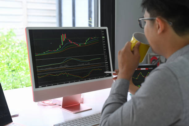 istock Businessman drinking coffee and checking stock market on desktop computer. 1337185076