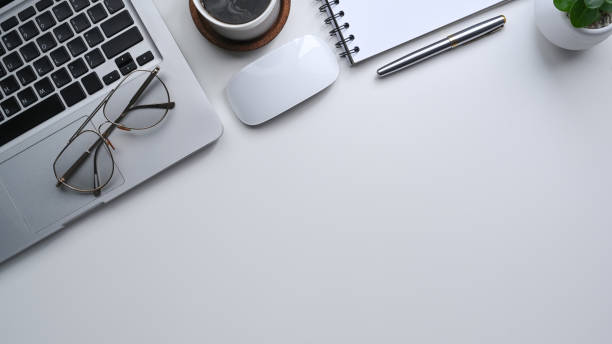 istock Top view laptop computer, glasses, notebook and glasses on white office desk. 1337185646