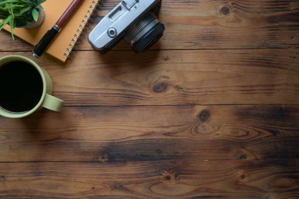 A retro camera, notebook and coffee cup on wooden table.