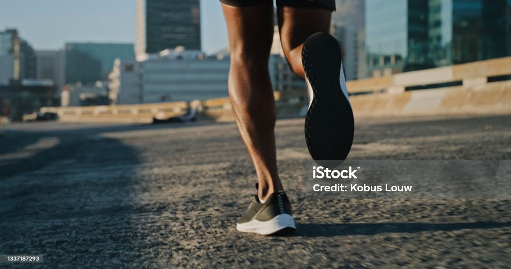 Closeup shot of an unrecognisable man running outdoors The road ahead will be tough, but you're strong Running Stock Photo