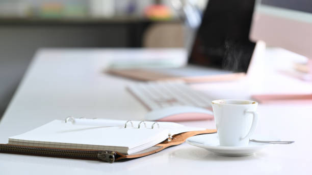 istock White cup of hot beverage and notebook on white office desk. 1337190319