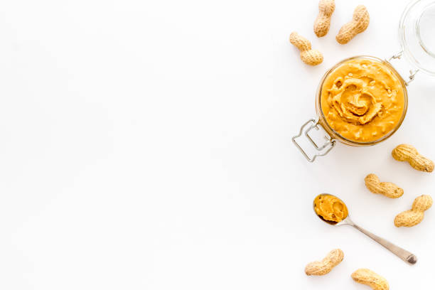 istock Creamy peanut butter in glass jar with nuts, top view 1337191559