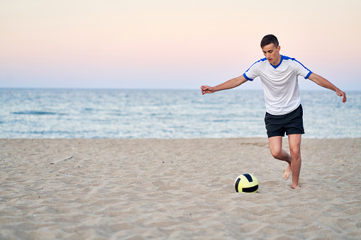 Teenager playing beach soccer