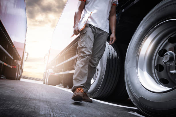 camionista che cammina e controlla le ruote e i pneumatici di un camion. ispezione manutenzione e sicurezza per la guida su camion. - truck tire foto e immagini stock