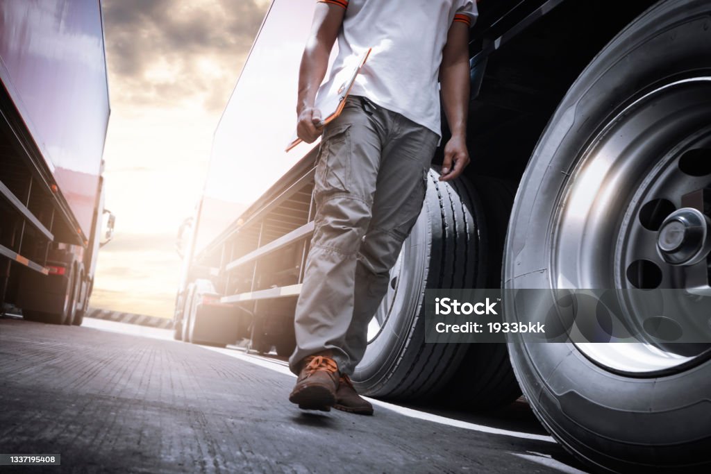 Truck Driver Walking and Checking A Truck Wheels and Tires. Inspection Maintenance and Safety forTruck Driving. Truck Stock Photo