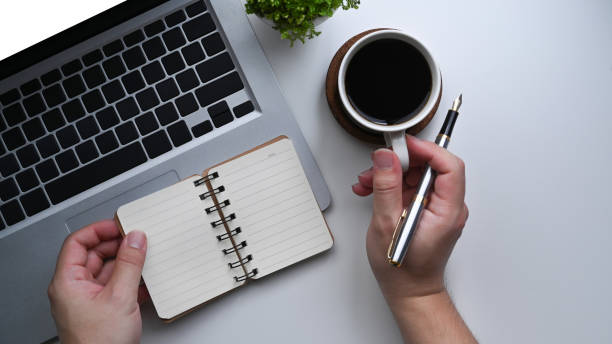 istock Businessman holding cup of coffee and making note on notebook. 1337195611
