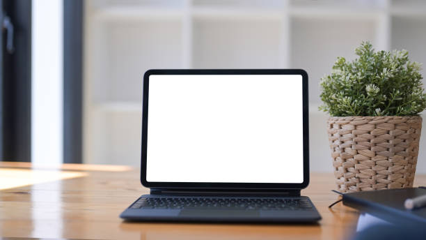 istock Mock up computer tablet with white display, houseplant and notebook on wooden desk. 1337195759