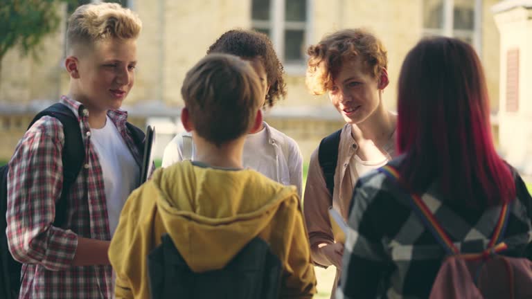 Happy school children talking and laughing, having fun together after classes