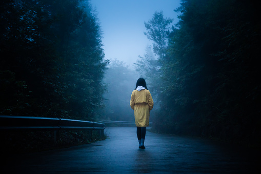Lonely woman is walking on fog road