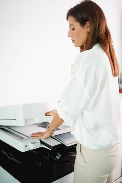 istock Woman loading photocopier with documents for making copies 1337204420