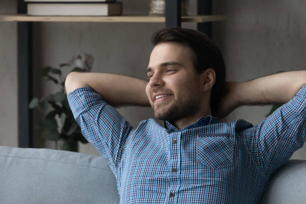 istock Happy thoughtful millennial guy relaxing on sofa at home 1337206383