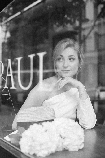 A well thought-out concept. Beautiful elegant woman in a cafe, looks through the window glass. Soft selective focus.