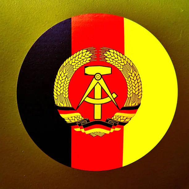 Coat of arms of the GDR, hammer, sickle and ears of grain on black-red-gold background, pasted on a military vehicle