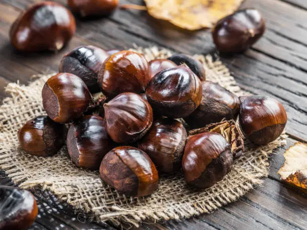 Photo of Roasted edible chestnut fruits on wooden table.