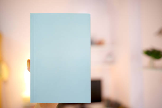 istock Holding a light blue book with a female hand with a blank cover for putting text on a blurry background. 1337209351