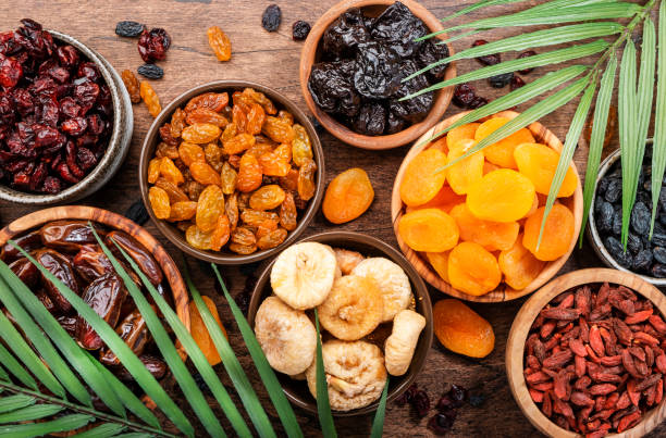 fruits secs naturels dans des bols. collation alimentaire saine: mélange biologique séché au soleil d’abricots, de figues, de raisins secs, de dattes et autres sur une table en bois, vue de dessus - dried apricot photos et images de collection