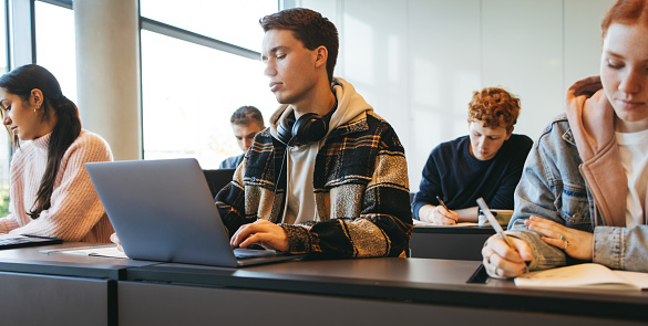 Teenage students sitting at desk in high school classroom. Group of young people during lecture in school.