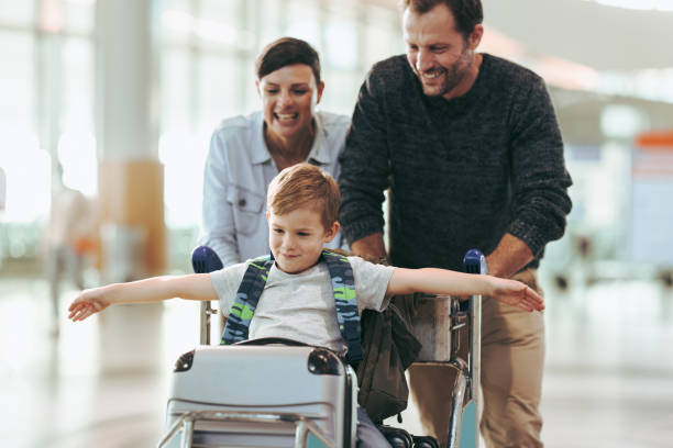 famiglia che si diverte durante l'attesa all'aeroporto - baggage wagon foto e immagini stock