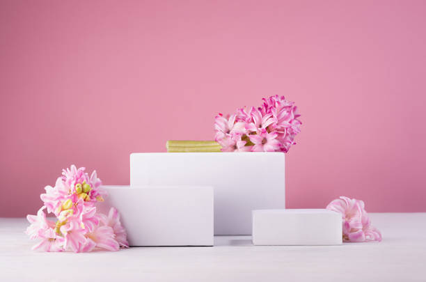 istock Three different square white podiums for display cosmetic produce or goods with fresh spring flowers and soft light pastel pink background. 1337210753