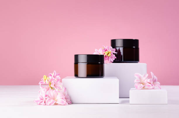 cosmetic mockup -  jars for cream of amber glass on white podiums with pink spring flowers. template for branding identity for cosmetics produce. - moisturizer cosmetics beauty treatment jar imagens e fotografias de stock