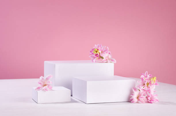 istock Three different square white podiums for display cosmetic produce or goods with fresh spring flowers and soft light pastel pink background. 1337210826